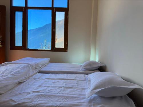 a bedroom with two beds with pillows and a window at hotel in manali by Aura in Vashisht