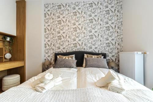 a bedroom with a white bed with a floral wallpaper at Buda Top Floor Apartment with Terrace & View in Budapest