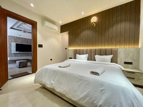a bedroom with a large white bed and a television at Marine Ganga Stays in Rishīkesh