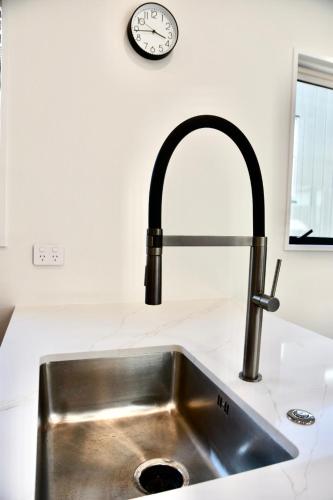 a sink in a kitchen with a clock on the wall at Modern 3BR Escape 3 Private Baths Rare Garage Perfect for Groups in Christchurch