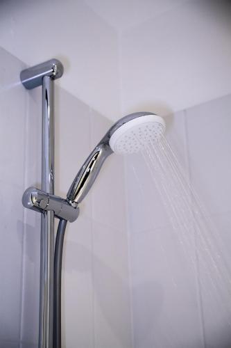 La salle de bains est pourvue d'une douche avec un pommeau de douche blanc. dans l'établissement Nid d'émeraude - Votre escale cosy à Haguenau, à Haguenau
