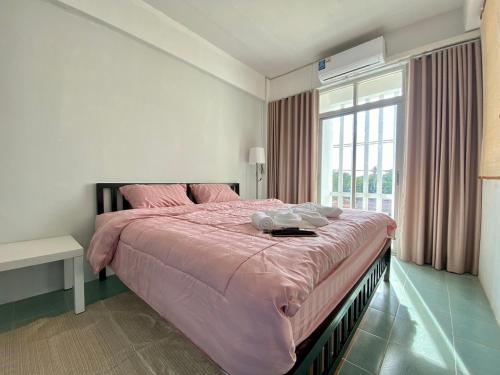a bedroom with a pink bed and a window at Baiyok House in Ban Ai Dao