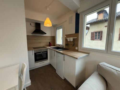 a small kitchen with white cabinets and a window at L'Écrin Bleu in Saint-Gaudens