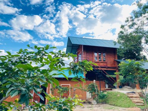 a red house with a black roof and trees at Lion Wood Treehouse in Talkote