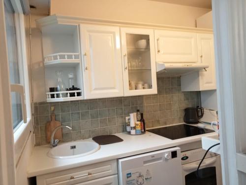 une cuisine avec des armoires blanches et un évier dans l'établissement Appartement 11e, à Paris
