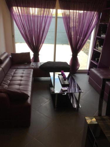 - un salon avec des rideaux violets et un canapé dans l'établissement Chez louloute, à Fréjus