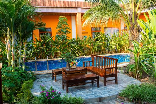 a patio with two wooden benches and a house at Rosa Garden in Ninh Binh