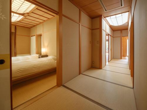 a room with a bed and a hallway with a window at Sekitaitei Ishida in Achi