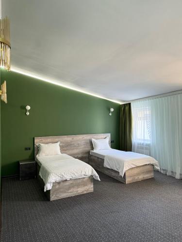 two beds in a room with green walls at Shygys_hotel in Aktau