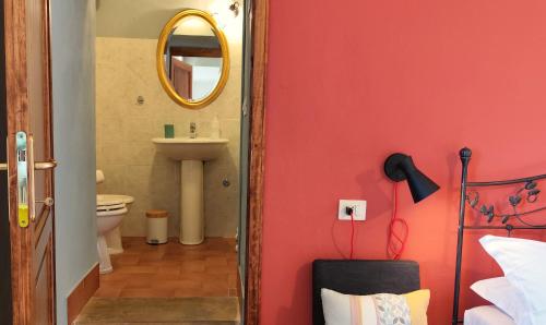 a bathroom with a red wall with a sink and a mirror at Podere Campiano in Volterra