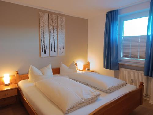 a bedroom with two beds and a window with blue curtains at 2-Raum FeWo Alpenglück - Hallenbad & Sauna in Fischen