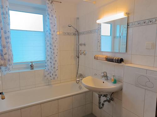 a bathroom with a sink and a bath tub and a mirror at 2-Raum FeWo Alpenglück - Hallenbad & Sauna in Fischen