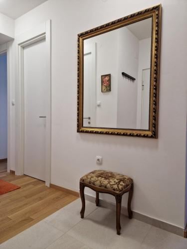 a mirror on a wall with a stool in a room at Stan na dan 34 in Banja Luka