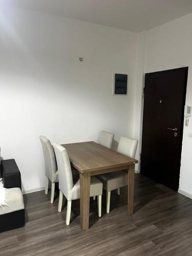 een eettafel met witte stoelen en een zwarte deur bij Amore in Ulcinj