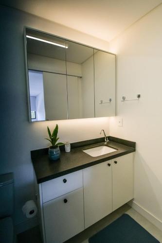 a bathroom with a sink and a mirror at Loft Novo Campeche in Florianópolis