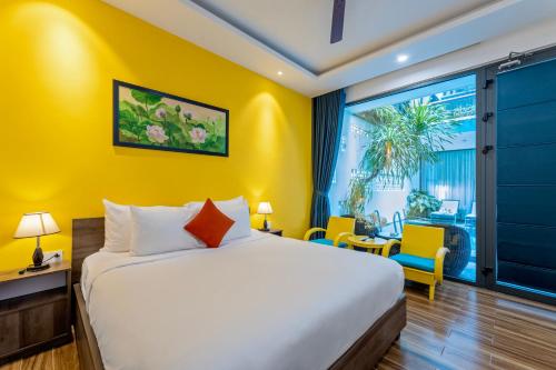 a bedroom with a bed and a yellow wall at The Nam An Villa Hoi An in Hoi An