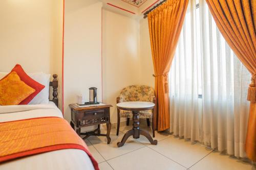 a bedroom with a bed and a table and a chair at Umaid Residency - A Regal Heritage Home in Jaipur