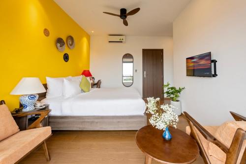 a bedroom with a white bed and a yellow wall at The Nam An Villa Hoi An in Hoi An