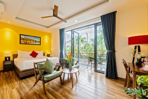 a hotel room with a bed and a table and chairs at The Nam An Villa Hoi An in Hoi An
