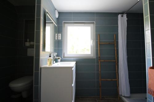 une salle de bain avec un lavabo et des toilettes et une fenêtre dans l'établissement Logement indépendant proche Saintes, à Fontcouverte