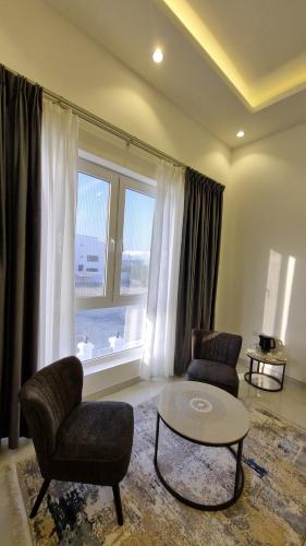 a living room with two chairs and a table and a window at Elizabeth in Muscat