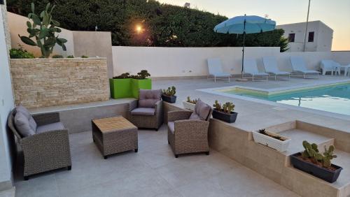 a patio with chairs and an umbrella and a pool at Villa Taliala in Alcamo Marina