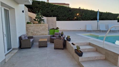 a patio with chairs and a swimming pool at Villa Taliala in Alcamo Marina