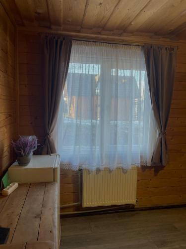 a window with curtains in a room with a bench at Khatky Na Penkakh in Vorokhta