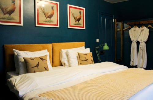 a bedroom with a bed with white sheets and chickens on the wall at Argyle Guest House in Tomintoul
