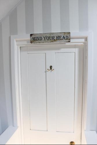 a sign above a white door with the words mind your head at Argyle Guest House in Tomintoul