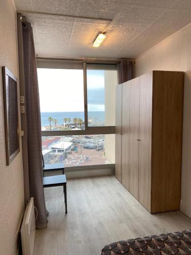 un salon avec une grande fenêtre et une chambre avec un bureau dans l'établissement Appartement à Saint-Cyprien Plage, à Saint Cyprien Plage