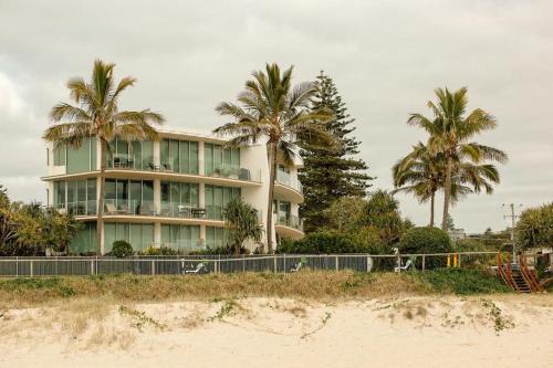 a building with palm trees in front of a beach at Waves 203 on Currumbin in Gold Coast