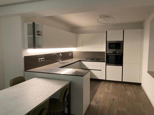 a kitchen with white cabinets and a sink and appliances at Domus Laita in Baselga di Pinè