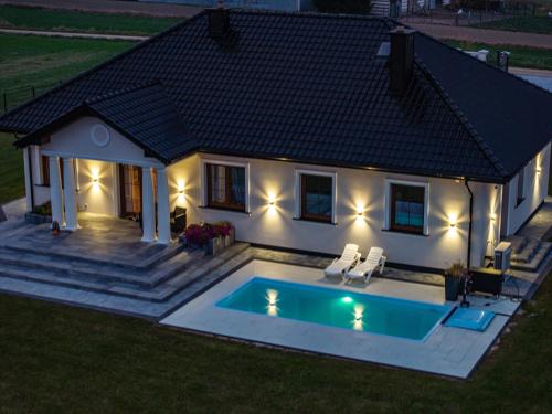 a house with a swimming pool in front of it at Dworek pod Krzyżtoporem Ujazd Agroturystyka- pokoje do wynajęcia in Iwaniska