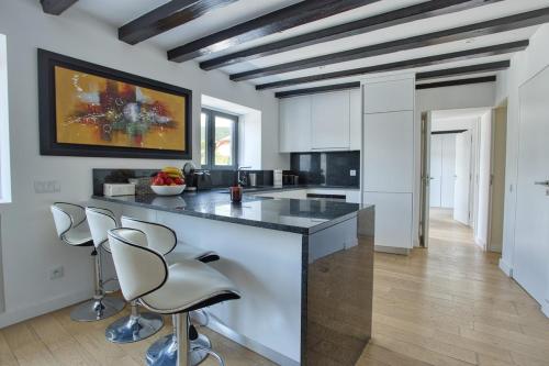 a kitchen with white cabinets and a counter with stools at HeberGenève Grilly Authentique in Grilly