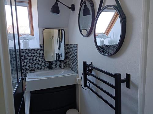 une salle de bain avec un lavabo et deux miroirs au mur dans l'établissement Ty Malauna Jacuzzi, à La Trinité-sur-Mer
