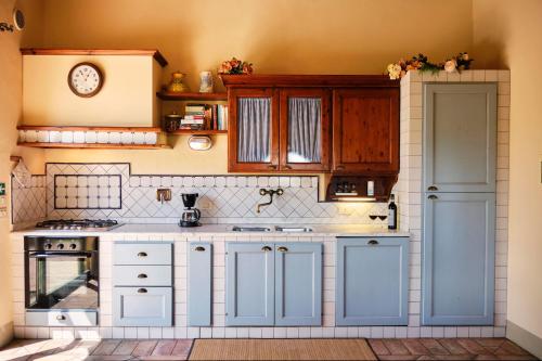 eine Küche mit weißen Schränken und einer Uhr an der Wand in der Unterkunft I Glicini - Casa vacanze con piscina in Toscana a 30' da Firenze in Tavarnelle in Val di Pesa