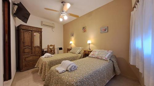 a bedroom with two beds and a ceiling fan at Hotel Albert in Villa Gesell