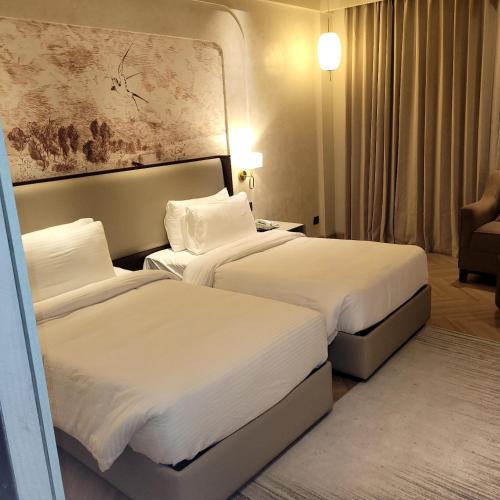 a hotel room with two beds and a couch at The Tivoli New Delhi in New Delhi
