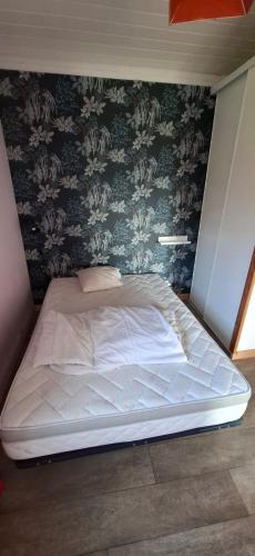 - un grand lit dans une chambre avec un mur dans l'établissement Appart Cosy à la Campagne, à Labarthète