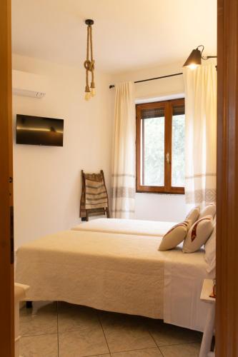 a bedroom with a bed with a window and a chair at Domo de Ciu Nenneddu in Oliena