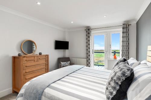 a bedroom with a bed and a dresser and a window at Blue Horizon - Spectacular Coastal Views in Penally