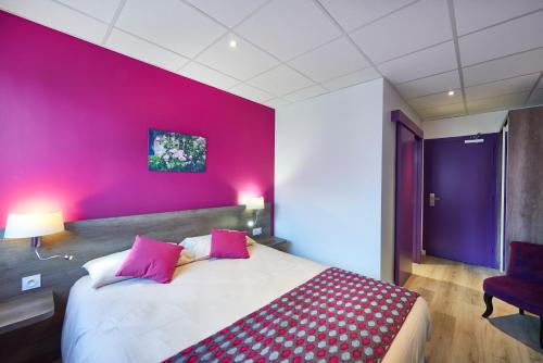 - une chambre avec un grand lit et un mur rose dans l'établissement Cozy Hôtel Logis Morlaix, à Plouigneau