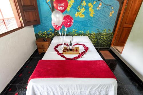 a room with a bed with a heart and balloons at Hotel Orillas del Pizano in Jardin