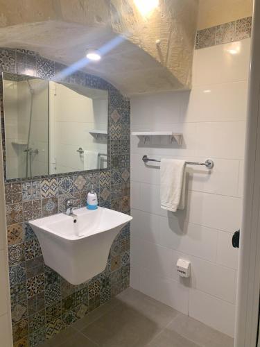 a bathroom with a sink and a mirror at Fiftyfour West Boutique Living in Għarb