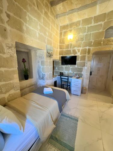 a bedroom with two beds and a stone wall at Fiftyfour West Boutique Living in Għarb