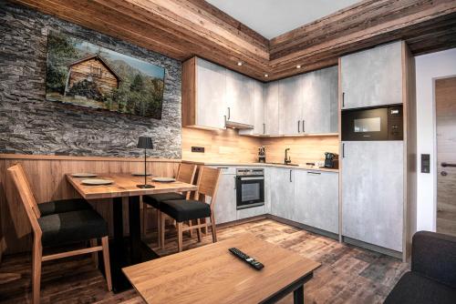 a kitchen with a wooden table and a dining room at AlpinSpa zur Post Apartment - Bergbahn im Sommer 2025 inklusive in Bad Gastein