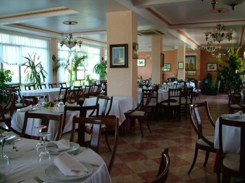 a restaurant with tables and chairs with white tablecloths at Hostal El Botero in Cuzcurrita-Río Tirón