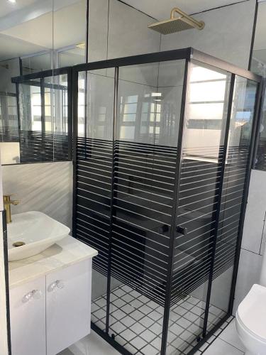a bathroom with a glass shower and a toilet at Humewood Gardens Private Suite in Gqeberha