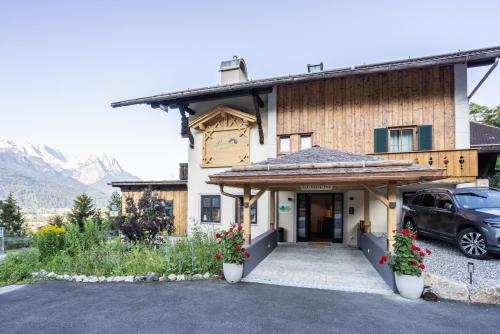 a house with a car parked in front of it at Landkomforthotel Panorama & Restaurant Bella Vista in Garmisch-Partenkirchen